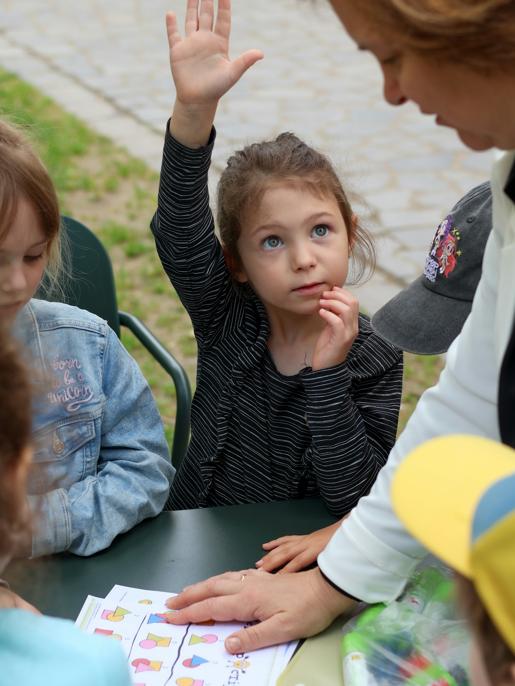 Vajzë që ngre dorën gjatë një aktiviteti me mësuesen